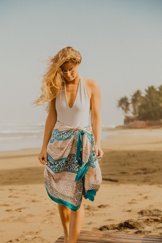 Woman on beach wearing Kaiilani Martinique blockprint sarong with blue and beige pattern on it.