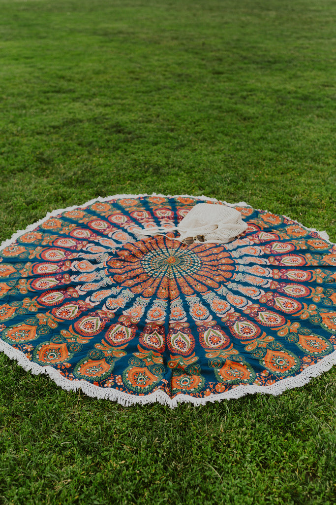The focus mandala with sunglasses and mesh beach bag laying on it, on the grass